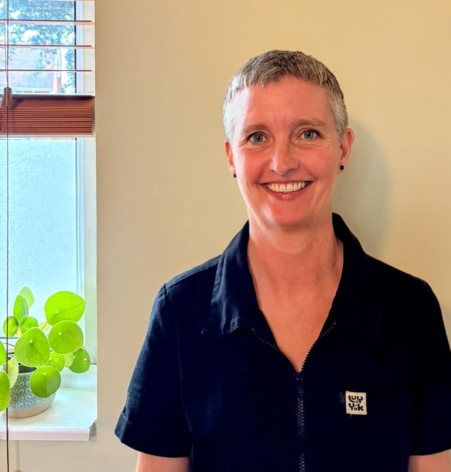 Vic, smiling, in front of a sunny window with a green plant